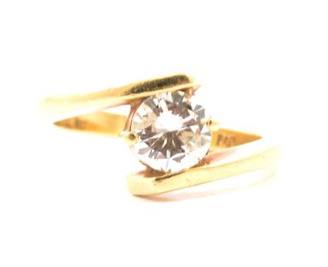 A diamond solitaire ring, the brilliant cut stone claw set in an all yellow metal crossover design mount, shank marked 18ct, 