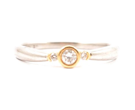 A diamond solitaire ring, the brilliant cut stone collet set in 18 carat yellow gold with a smaller diamond to each side to t