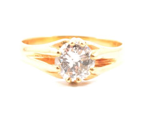 A diamond solitaire ring, the brilliant cut stone claw set in an all yellow metal mount with wide shoulders terminating in cl