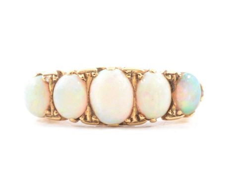 An opal half hoop ring, the five cabochon cut opals graduating in size claw set in an all yellow metal carved claw mount ring