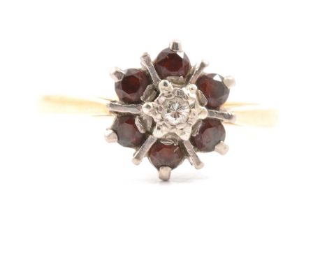 A garnet and diamond cluster ring, six garnets claw set and a brilliant cut diamond illusion set in a yellow and white metal 