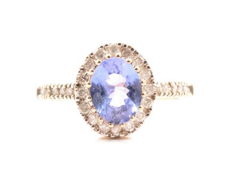 A tanzanite and diamond cluster ring, the oval mixed cut tanzanite approx. 9mm x 7mm claw set, surrounded by sixteen small ro
