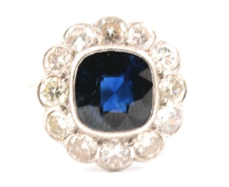 A sapphire and diamond cluster ring, the cushion shaped sapphire, 7x7.5mm, millegrain set and surrounded by twelve old cut di