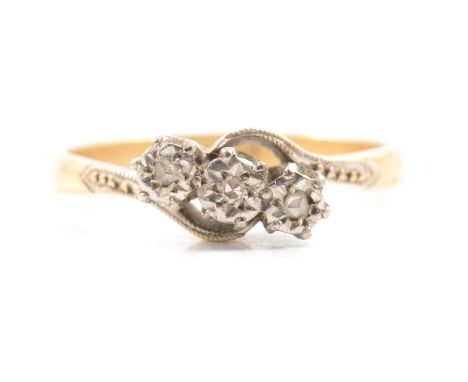 A diamond three stone crossover ring, one 8 cut diamond and two rose cut diamonds illusion set in a yellow and white metal tr