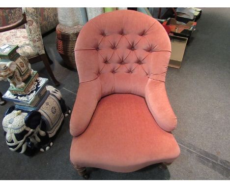 A Victorian button back armchair the serpentine front seat over turned legs and ceramic castors