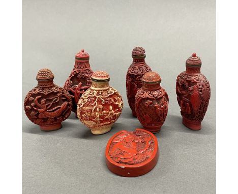 A group of six Chinese cinnabar and cinnabar type snuff bottles and cinnabar amulet, tallest 8cm.