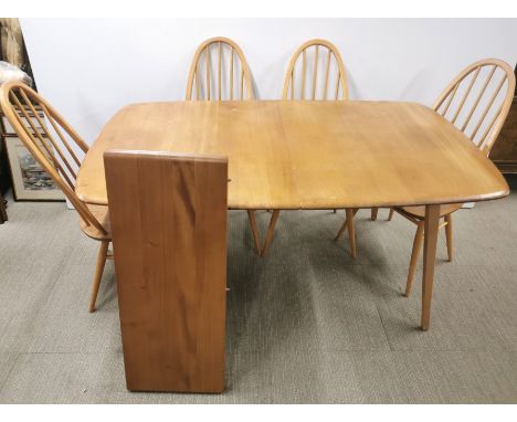 An Ercol extending blonde elm dining table raised on tapering legs with a set of six Ercol blonde elm Quaker stick back chair