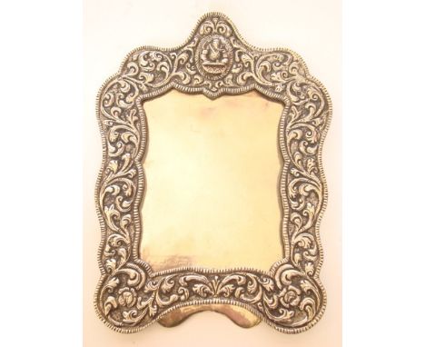 An Indian white metal photograph frame, of rectangular form, the shaped surround foliate chased with easel back, aperture 8cm