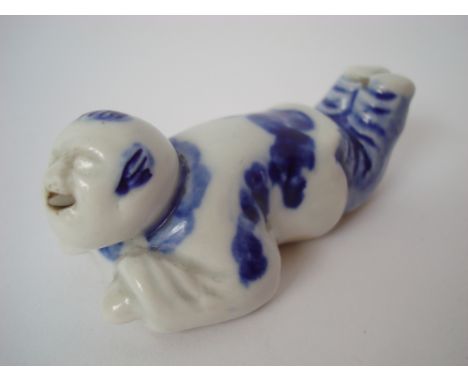 A Japanese Hirado blue and white Hirado porcelain Netsuke, modelled as a boy lying prone with his feet in the air and with op