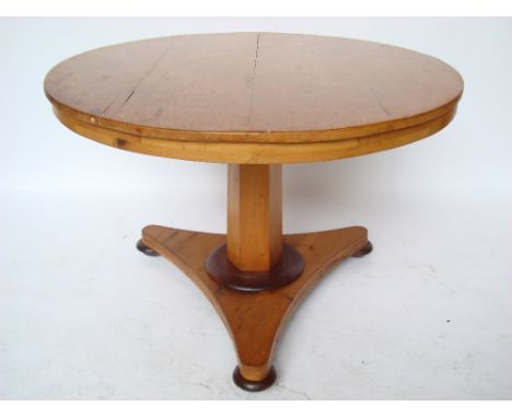 An early Victorian pine breakfast table, the circular top with tilt action, on tapering hexagonal stem and triform base on co