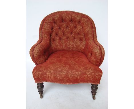 A Victorian low armchair, with buttonback upholstered back and low arms over a serpentine padded seat, on turned forelegs nd 