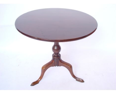 A George III mahogany tripod table, the circular top with tilt action on baluster stem and three cabriole legs with pointed p