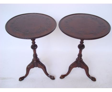 A pair of George III style mahogany tripod tables, each with fixed circular top with a moulded edge and carved with a foliate