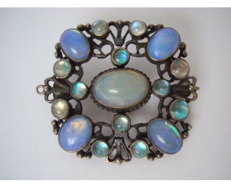 An Arts and Crafts opal and moonstone brooch in the manner of Amy Sandheim, the central oval cabochon stone enclosed by a squ