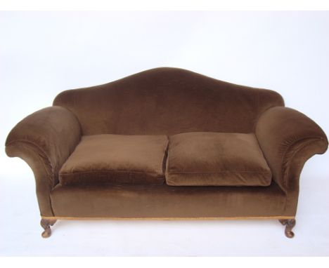 An early 20th Century hump back sofa, with scroll arms, on shell capped squat cabriole legs and pad feet, with squab cushions