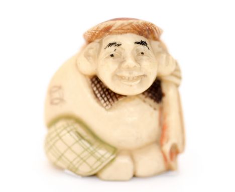 A 19th century Japanese carved ivory polychrome netsuke, in the form of man holding a sack, wearing a Scottish flatcap