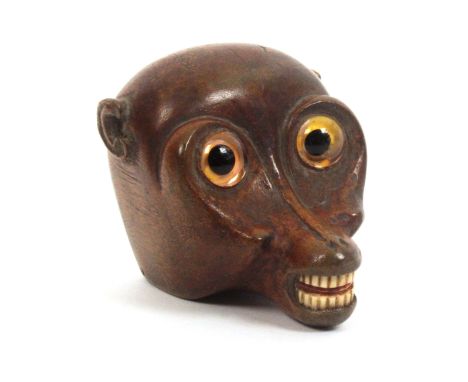 An early 19th Century carved wood snuff box in the form of an exaggerated monkey head, large glass eyes, bone teeth, the rear