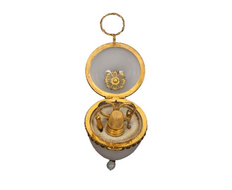 A late 19th Century French opaque glass egg form sewing etui for a child, gilt metal hinge mount, the base with pendant drop,