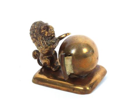 A gilt brass novelty tape measure in the form of a lion, its paws resting on a ball, emblematic of a globe, the complete prin