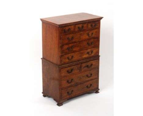 An attractive walnut miniature chest on chest, circa 1920, the lower section on ogee bracket feet and fitted with two short a