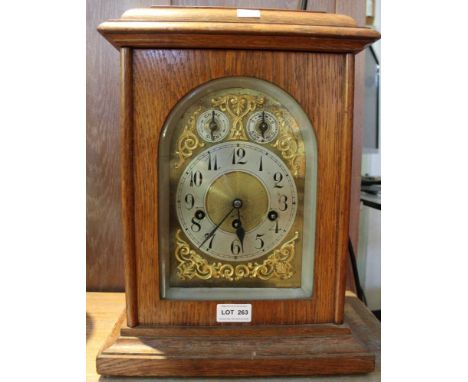 An oak cased ornate brass dial bracket clock with key and pendulum