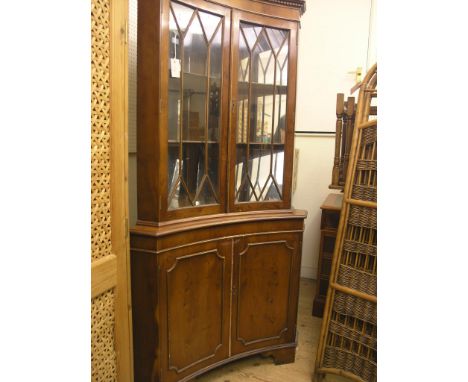 A yew-veneered corner cabinet, floor-standing, pair of glazed doors enclosing mirrored interior, panelled cupboard base, 6ft.