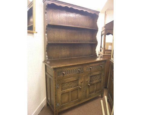 A solid, dark oak Welsh dresser, twin-shelf plate rack above carved and panelled cupboard base with two drawers, 4ft. 3in. 