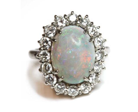 A white gold opal and diamond cluster ring, with an oval cabochon opal double claw set, to surround of sixteen brilliant cut 