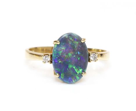 A three stone black opal and diamond ring,with an oval cabochon black opal, four claw set to a plain collet. A brilliant cut 