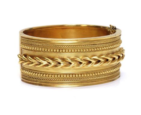 A cased Victorian gold archaeological revival, Etruscan style hinged bangle, c.1860,of oval hinged form. A flat section bangl