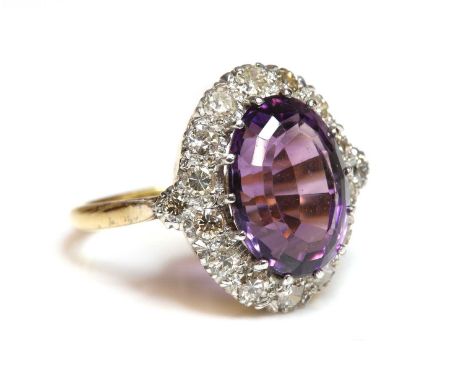 An amethyst and diamond oval cluster ring,with an oval Brazilian cut amethyst, claw set to the centre. A border of Swiss cut 