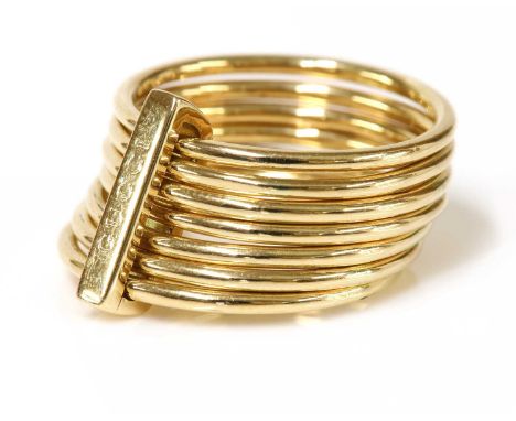 An 18ct gold seven row ring, by Gucci,with seven circular section bands, all joined by a bar signed Gucci. Signed Gucci made 