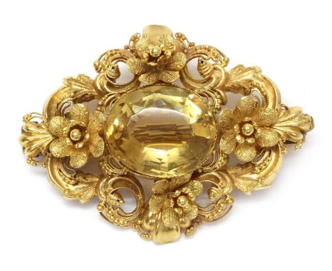 A Victorian gold citrine brooch, c.1840,of scrolling lozenge form. An oval mixed cut citrine, claw set to the centre, with te
