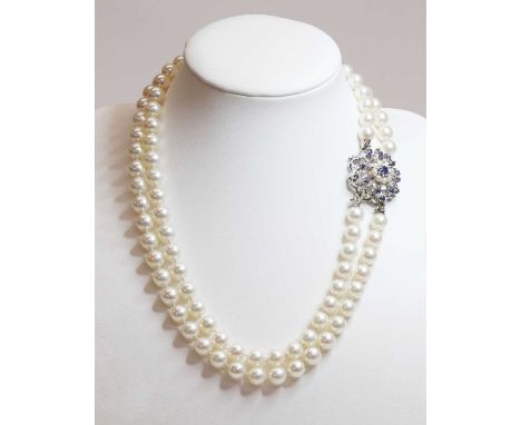 A two row uniform cultured pearl necklace, with a sapphire and cultured pearl cluster clasp, c.1950. Two rows of uniform cult