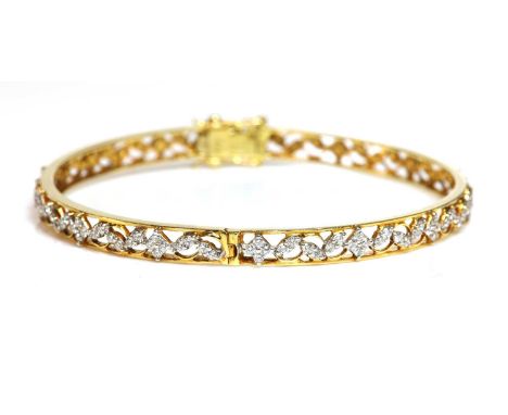 An 18ct gold diamond set hinged bangle,with pairs of brilliant cut diamonds, claw set between quatrefoil clusters of brillian