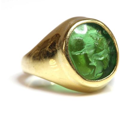 An 18ct gold intaglio signet ring,with a green glass intaglio depicting a matador riding a bull, rub set to the a plain mount