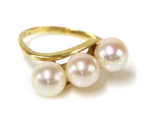 A three stone cultured pearl crossover ring, by Mikimoto,with three 6.5 to 7mm cultured pearls, peg set between crossover sho