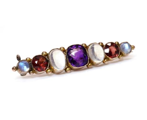 A gold seven stone graduated assorted gemstone gold brooch, c.1900,with a cushion cut amethyst, set to the centre. An oval ca