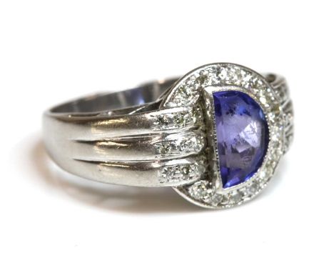 A tanzanite and diamond ring, c.1940,with a lunette cut later tanzanite, rub set to the centre. A crescent border of old Swis