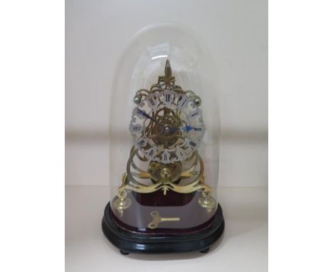 A brass skeleton clock with a chain driven fusee movement under a glass dome with wooden stand, 40cm tall x 24cm wide, with k