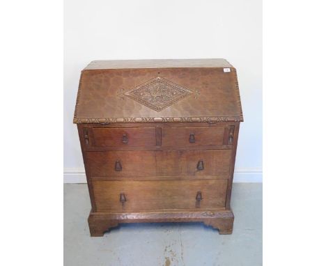 A Robert Mouseman Thompson style adzed oak four drawer bureau with a carved Welsh Dragon on the fall front standing on bracke