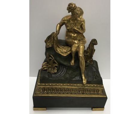 A 19th Century Continental bronze and gilt bronze figure of a nude Classical maiden with drape seated upon a rock, her left f