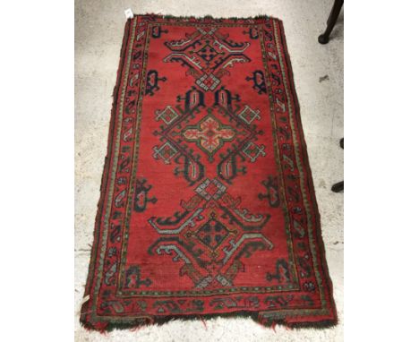 A Turkish rug, the central panel set with repeating motifs on a red ground, within a stepped red, green and gold scrolling fo