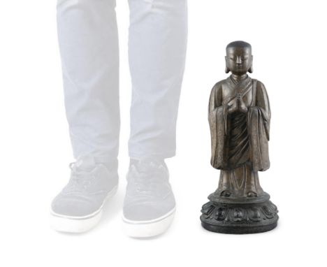 A HEAVY CASTED BRONZE FIGURE OF A STANDING ATTENDANT OR MONK China, Ming Dynasty The attendant or monk standing on a lotus ba