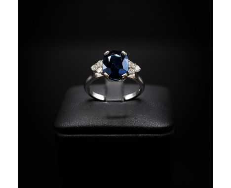AN 18CT WHITE GOLD SAPPHIRE AND DIAMOND RING, the large oval mixed cut sapphire flanked by six round brilliant cut diamonds, 