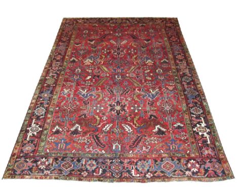 FINE PERSIAN HERIZ CARPET, 325cm x 230cm, geometric palmettes, flowerheads and vines on a terracotta field inside a correspon