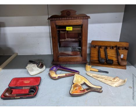 An oak smoker's cabinet with bevelled glass panelled front, fitted interior with drawers, and tobacco pipes, oak pipe rack wi