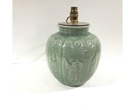 A Chinese celadon glazed jar, possibly a wine jar, moulded with panels enclosing figures beneath a ruyi frieze, impressed sea