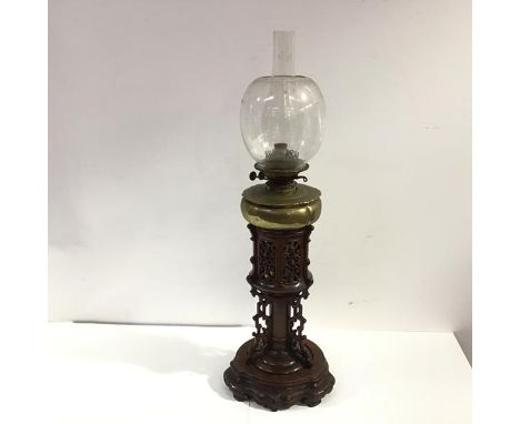 An unusual Chinese fret-carved wooden and brass oil lamp, c. 1900, the elaborately carved and pierced body on a shaped circul