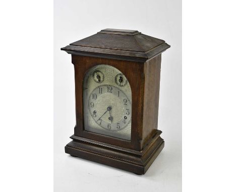 A late 19th/early 20th century German stained pine cased mantel clock, the decorated silvered dial set with applied chapter r